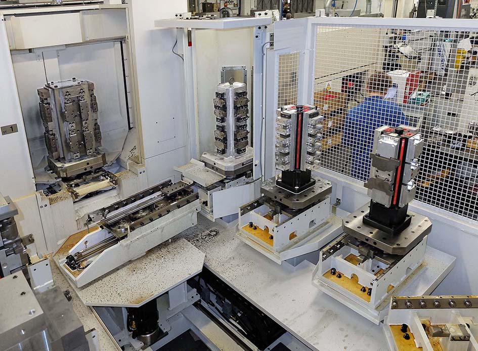 Another view of the Okuma FMC pallet pool, showing one of the cast iron tombstones in the machine ready for pallet exchange equipped with OK-Vise heavy duty, expanding clamps. An Abbott Tenzaloy tombstone is in the load/unload station. To the right are two Chick tooling columns with faceplates and, far right, Qwik-Lok twin-station, fast-acting jaws.